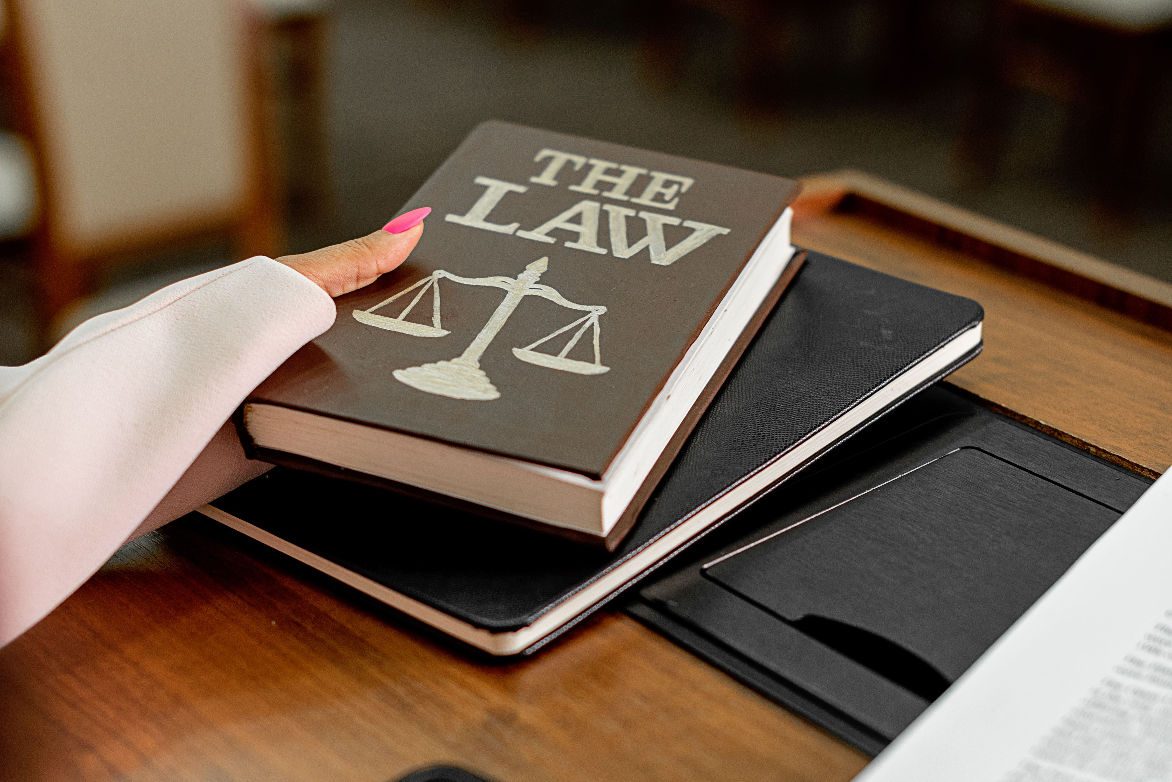 A law book beside scales of justice on a wooden desk, representing the legal framework behind large group claims