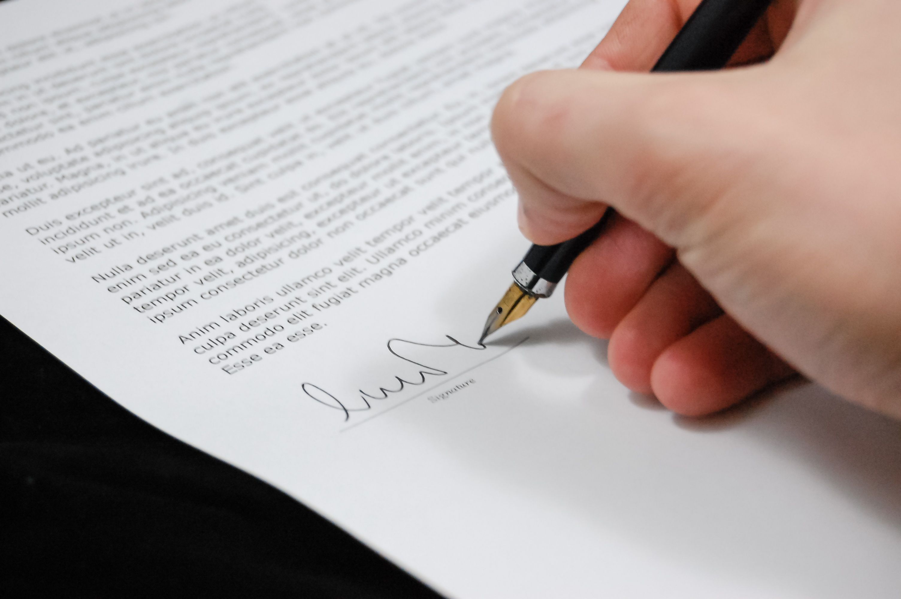 Close-up of a hand signing a legal document with a fountain pen, symbolizing joining a group claim agreement